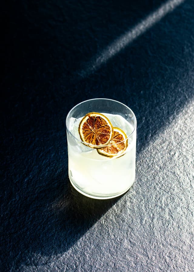 Een lichte margarita met een gedroogd schijfje limoen, in laag avondlicht